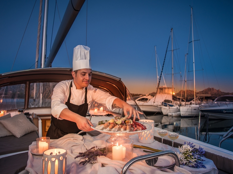 Chef presenting a fresh seafood platter on board at sunset