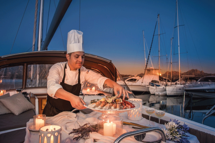 Chef presenting a fresh seafood platter on board at sunset